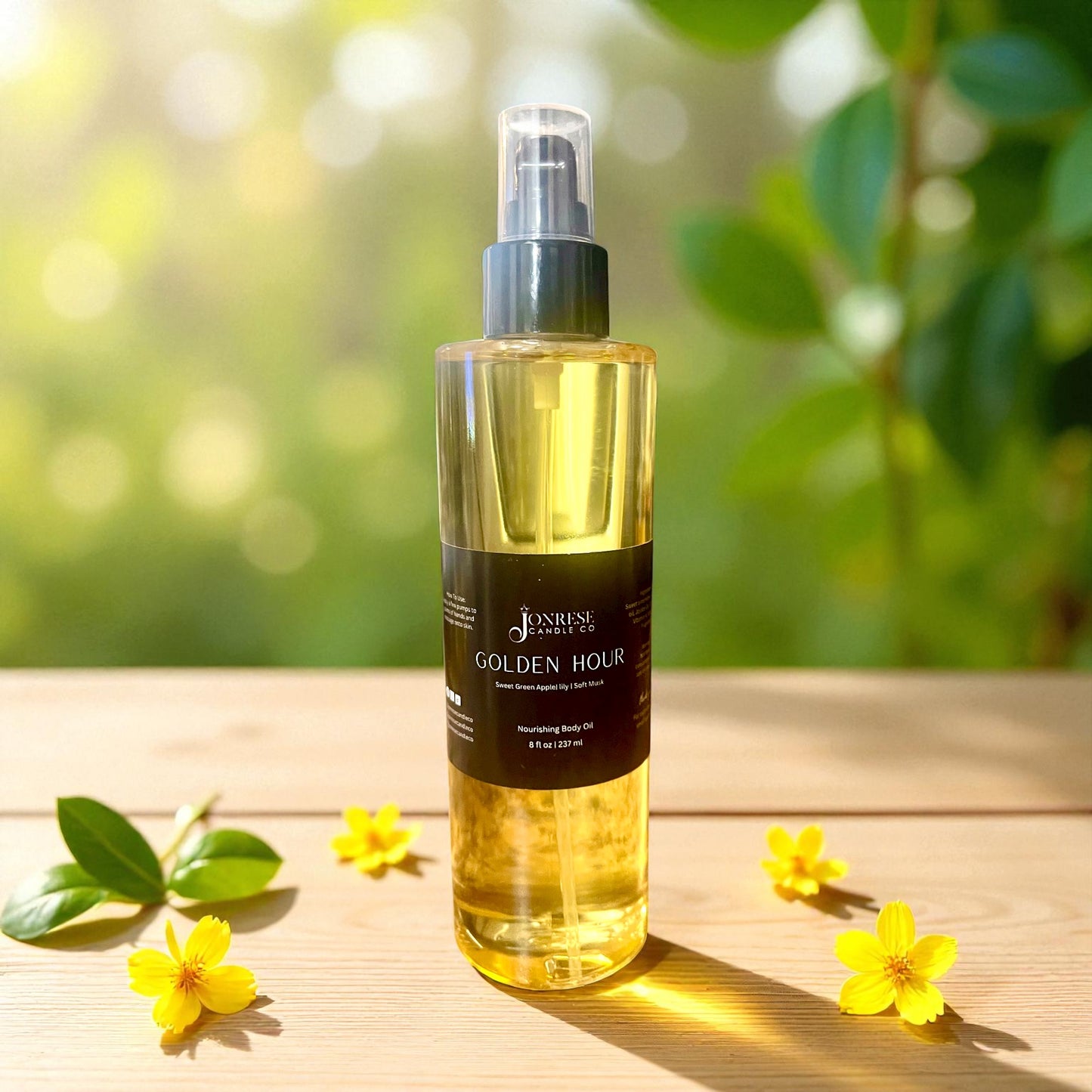 Bottle of 'Golden Hour' body oil on a wooden surface with flowers and greenery in the background