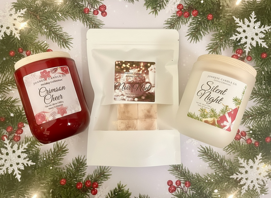 Two holiday-themed candles and one Holiday themed package of Wax Melts on a decorative background with greenery and snowflakes.