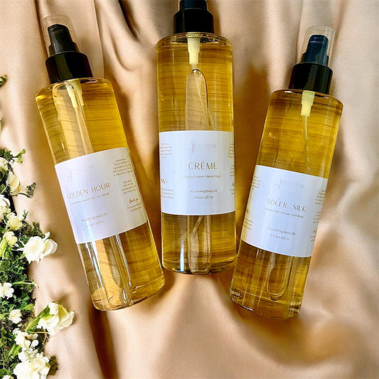 Three bottles of body oil product on a beige fabric background with flowers.