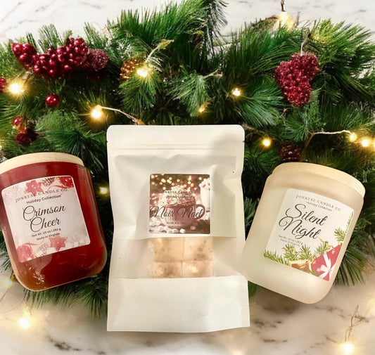 Two candles and a package of Wax melts with holiday-themed labels on a decorative background with lights and greenery.