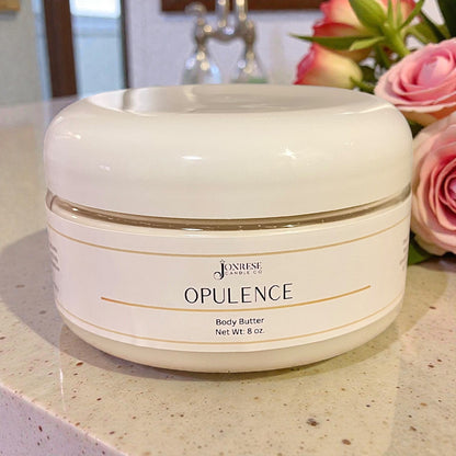 White jar of Joorese Opulence Body Butter on a countertop with flowers in the background