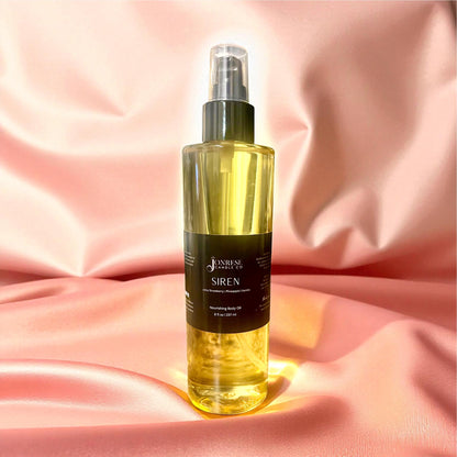 Bottle of 'Siren' body oil on a pink fabric background